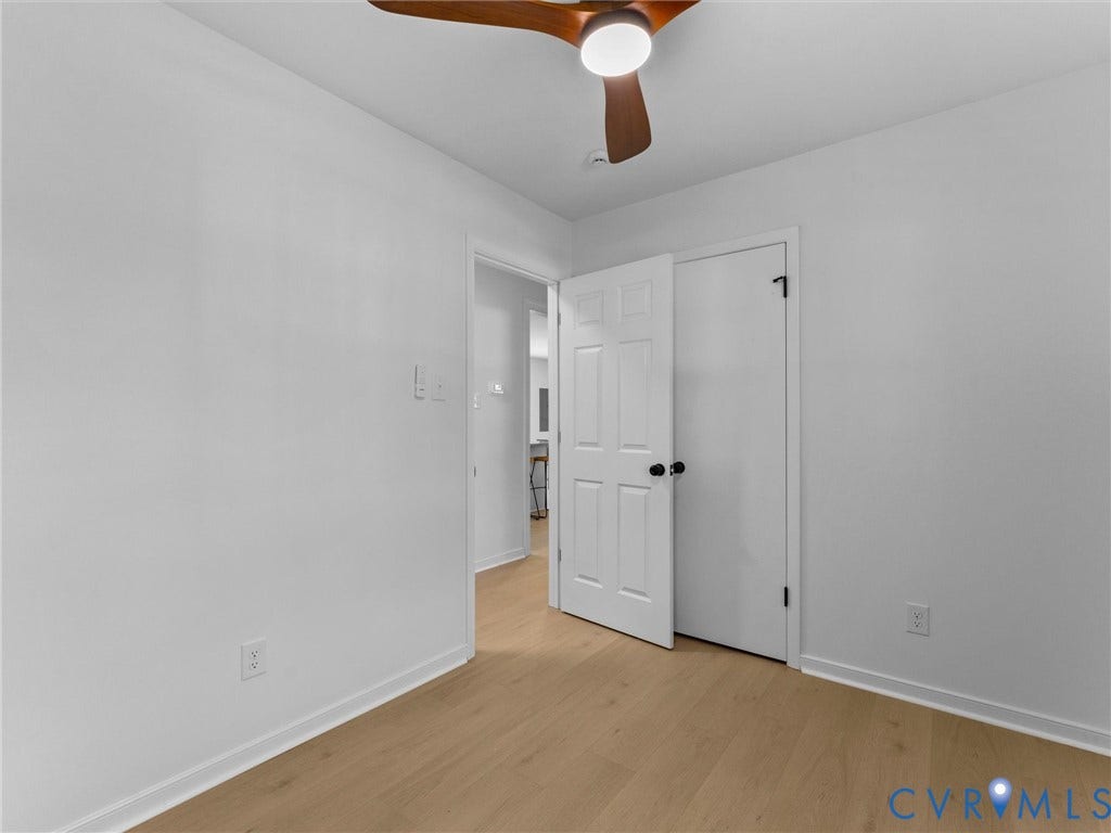 Light wood-finish flooring, white walls, white doors, and a ceiling fan with integrated lighting
