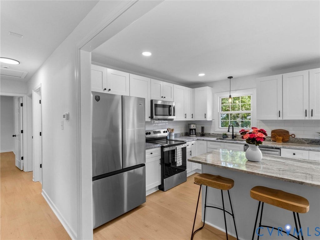 Bright kitchen featuring white cabinetry, stainless steel appliances, a subway tile backsplash, and light wood-finish flooring