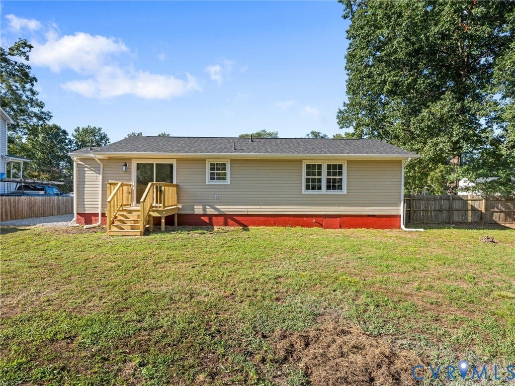 Rear exterior featuring beige siding, a wood-finish deck, sliding glass door, and a shingled roof