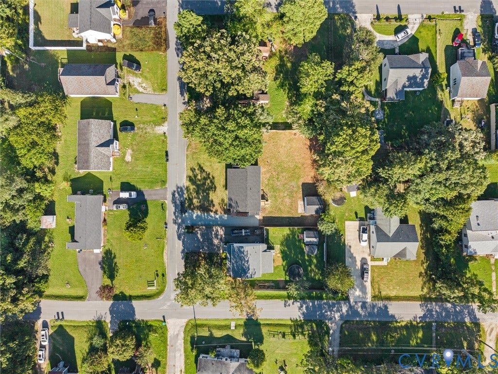 Aerial perspective showcasing multiple residential properties, street grid, mature trees, and manicured lawns