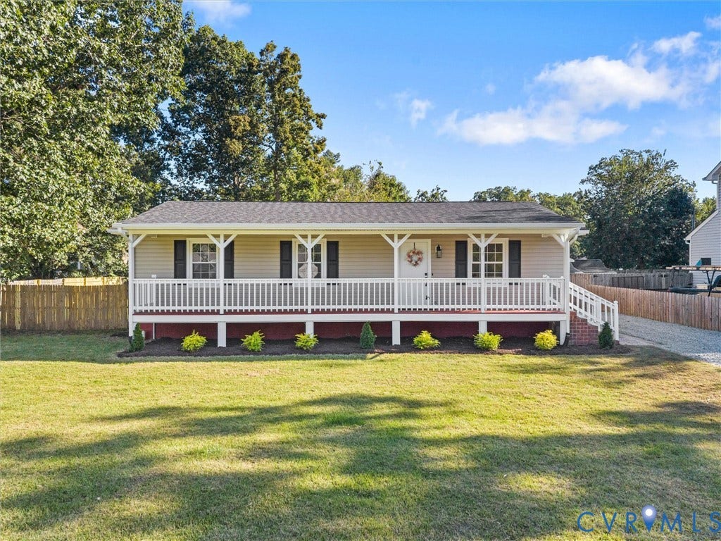Front exterior with a covered porch, vinyl siding, shuttered windows, a gravel driveway, and a fenced perimeter