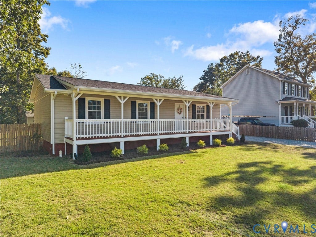 Ranch-style residence featuring a covered front porch, light-colored siding, and dark window shutters