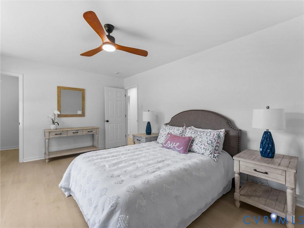 Light wood-finish flooring, white walls, and a ceiling fan with integrated lighting