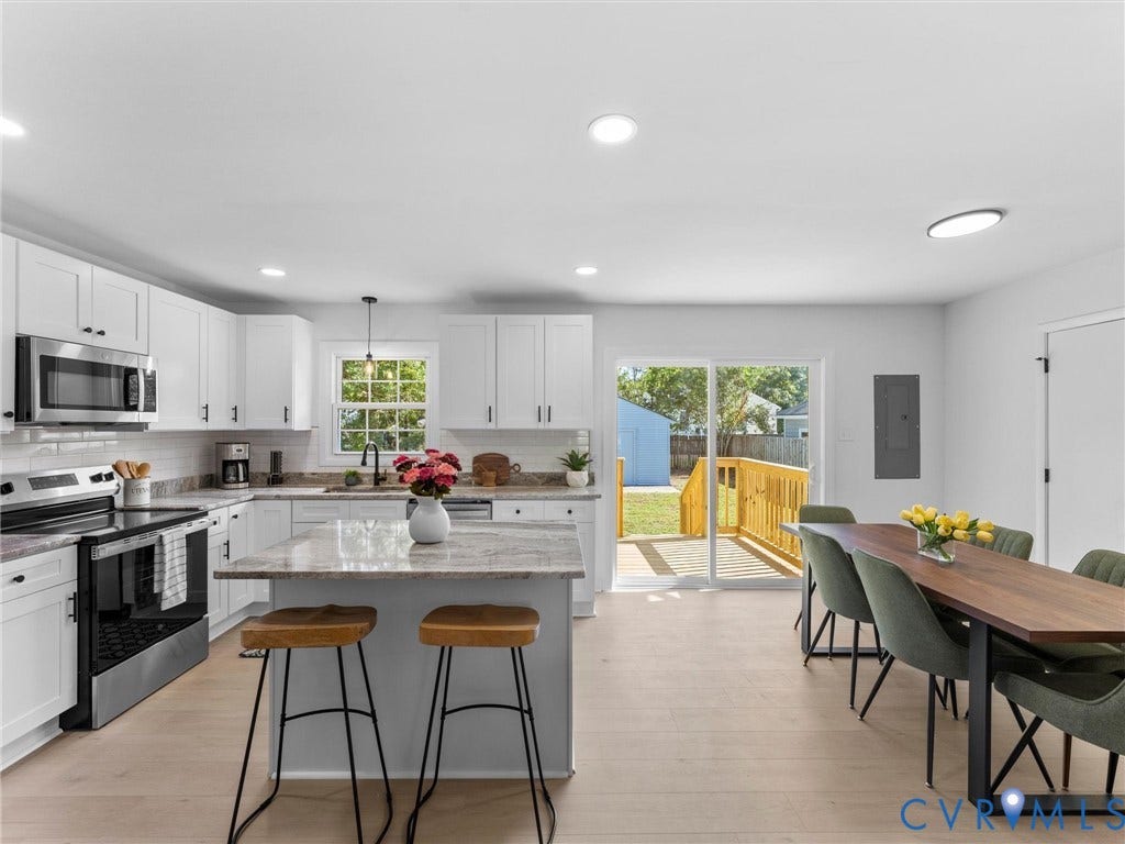 Kitchen featuring white cabinetry, stainless steel appliances, a kitchen island with seating, and wood-finish flooring