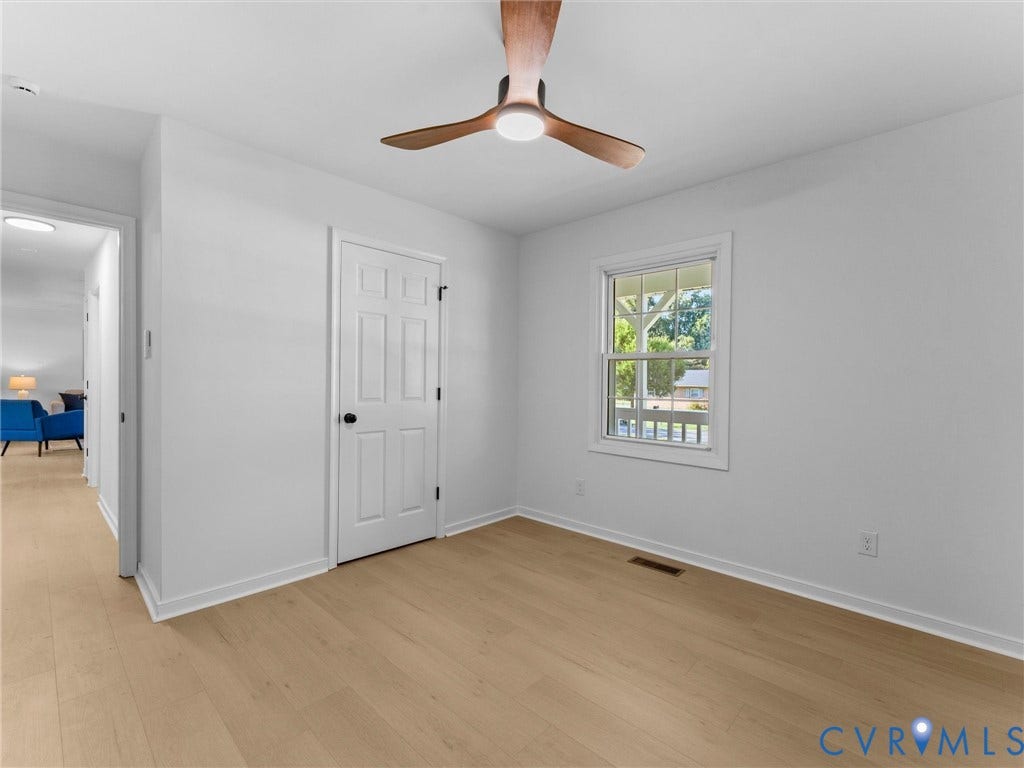 Light wood-finish flooring, white walls, and a modern ceiling fan with a light fixture