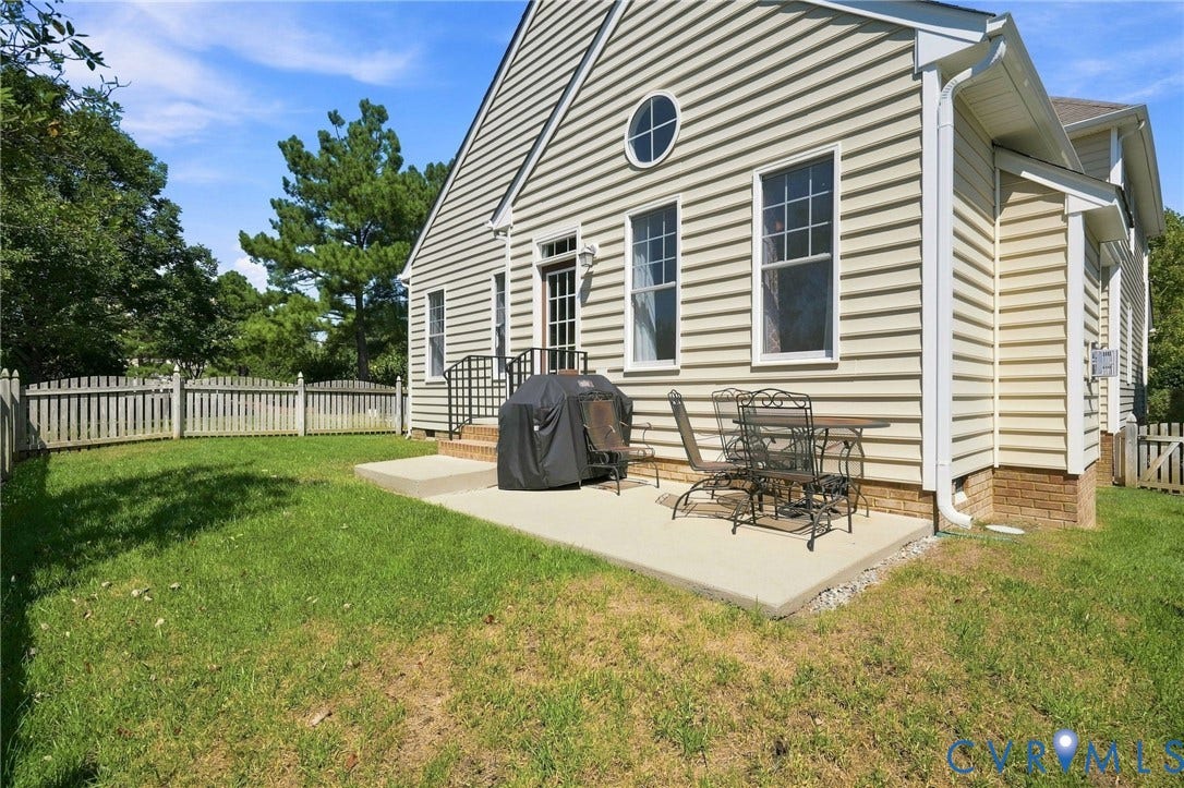 Charming Colonial-style home with cream horizontal siding and black shutters, featuring a covered front porch with columns