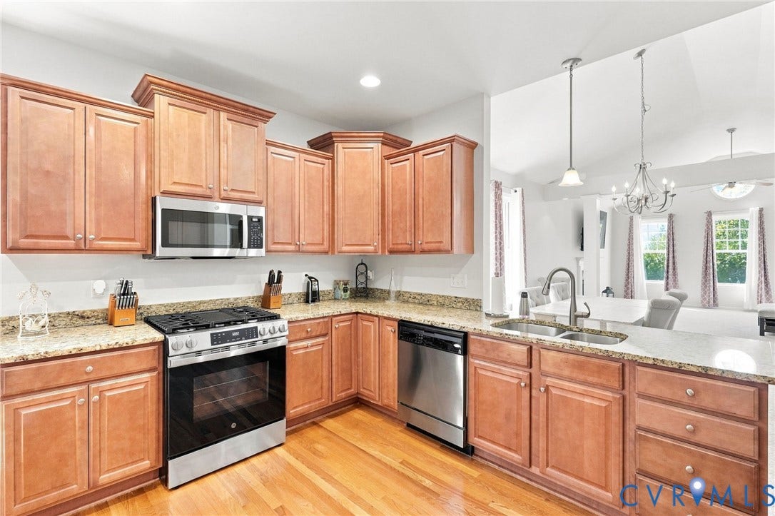 Kitchen featuring wood cabinetry, stainless steel appliances, speckled countertops, and wood-finish flooring