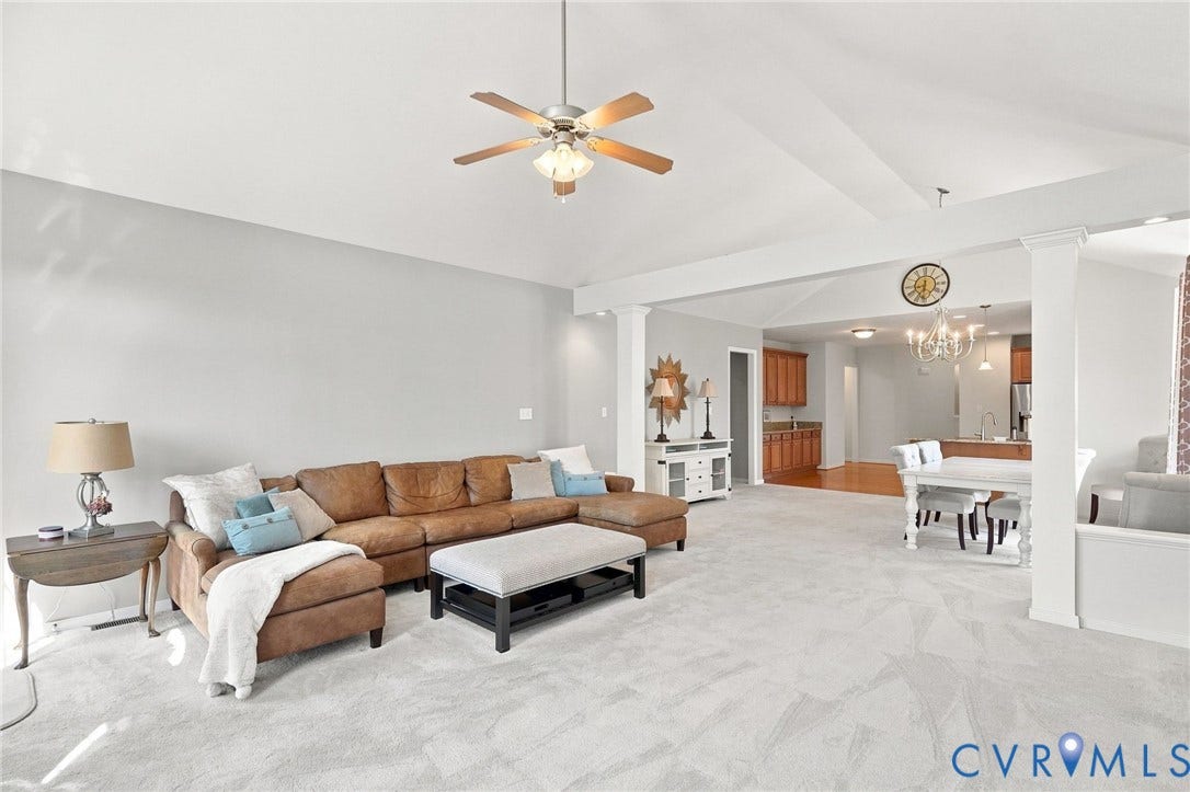 Vaulted ceiling with a ceiling fan, light gray wall finishes, and light-toned carpeting