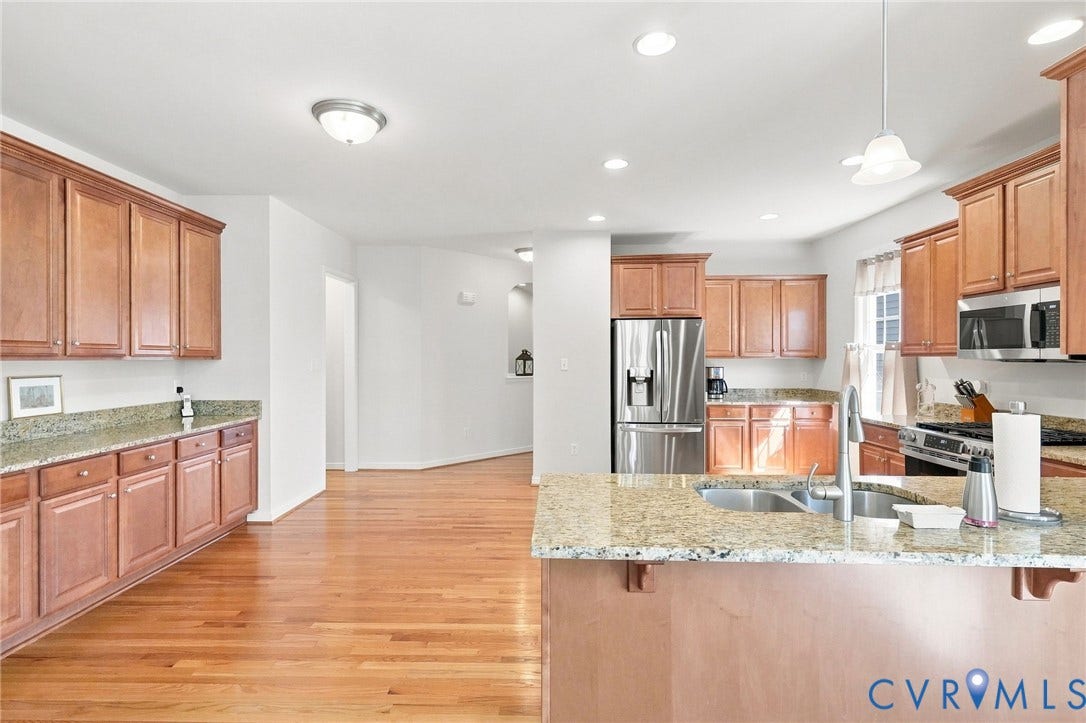 Hardwood flooring, light wood cabinetry, granite countertops, stainless steel appliances, and recessed lighting