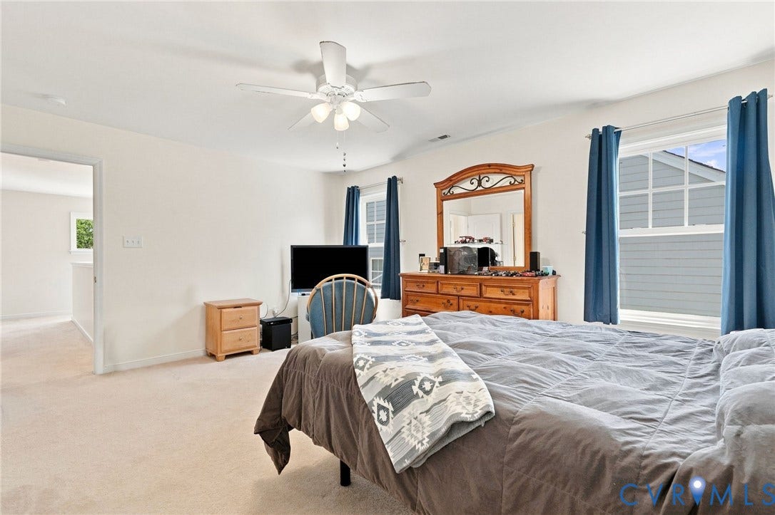 Neutral-toned carpeting, white walls, and a ceiling fan with integrated lighting