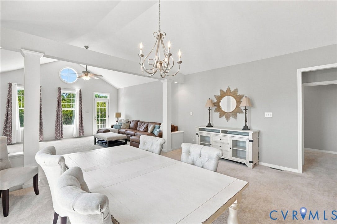 Vaulted ceilings, a decorative chandelier, and an oval transom window enhance this bright living area
