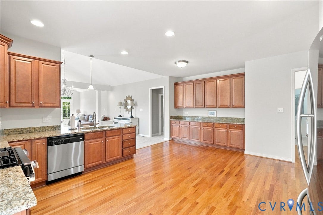 Kitchen with wood-finish flooring, recessed lighting, wood cabinetry, stainless steel appliances, and stone countertops
