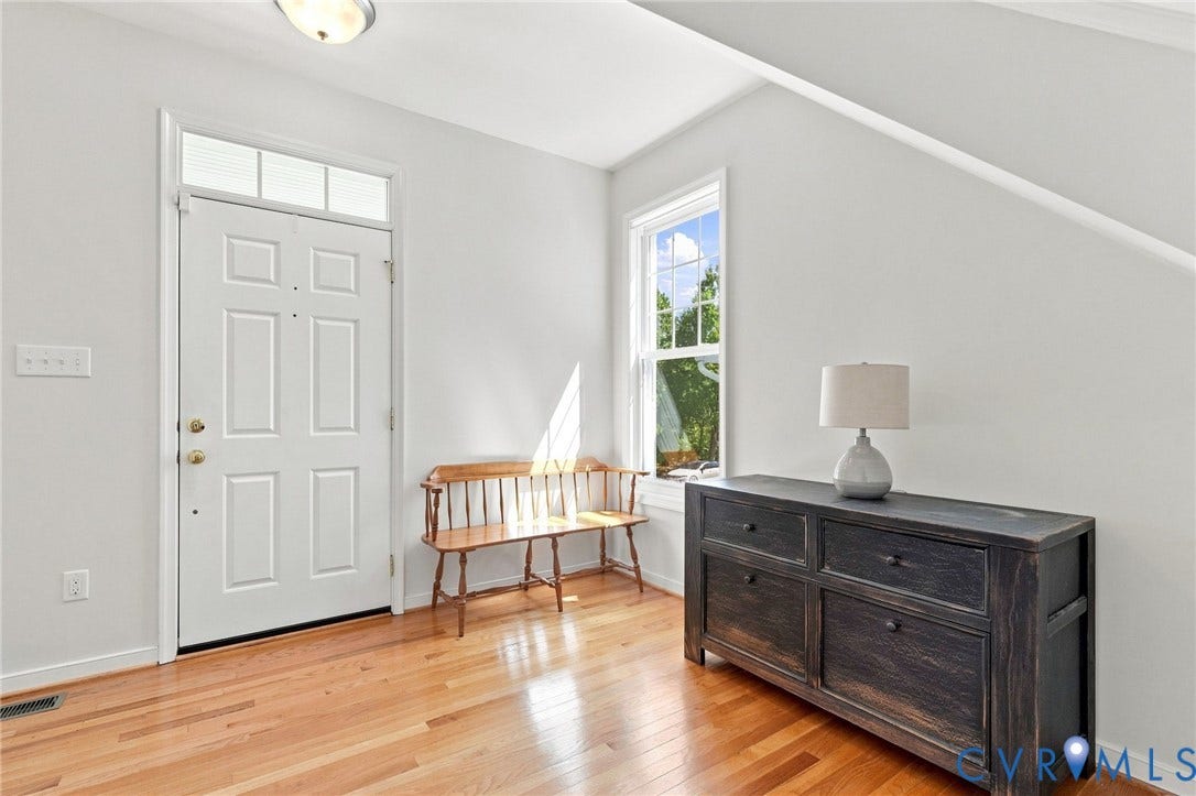 Solid wood-finish flooring, white paneled door with transom, and a double-hung window