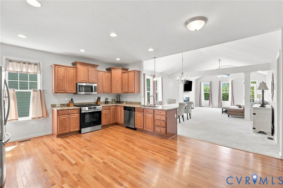 Hardwood flooring, wood cabinetry, stainless steel appliances, recessed lighting, and vaulted ceilings