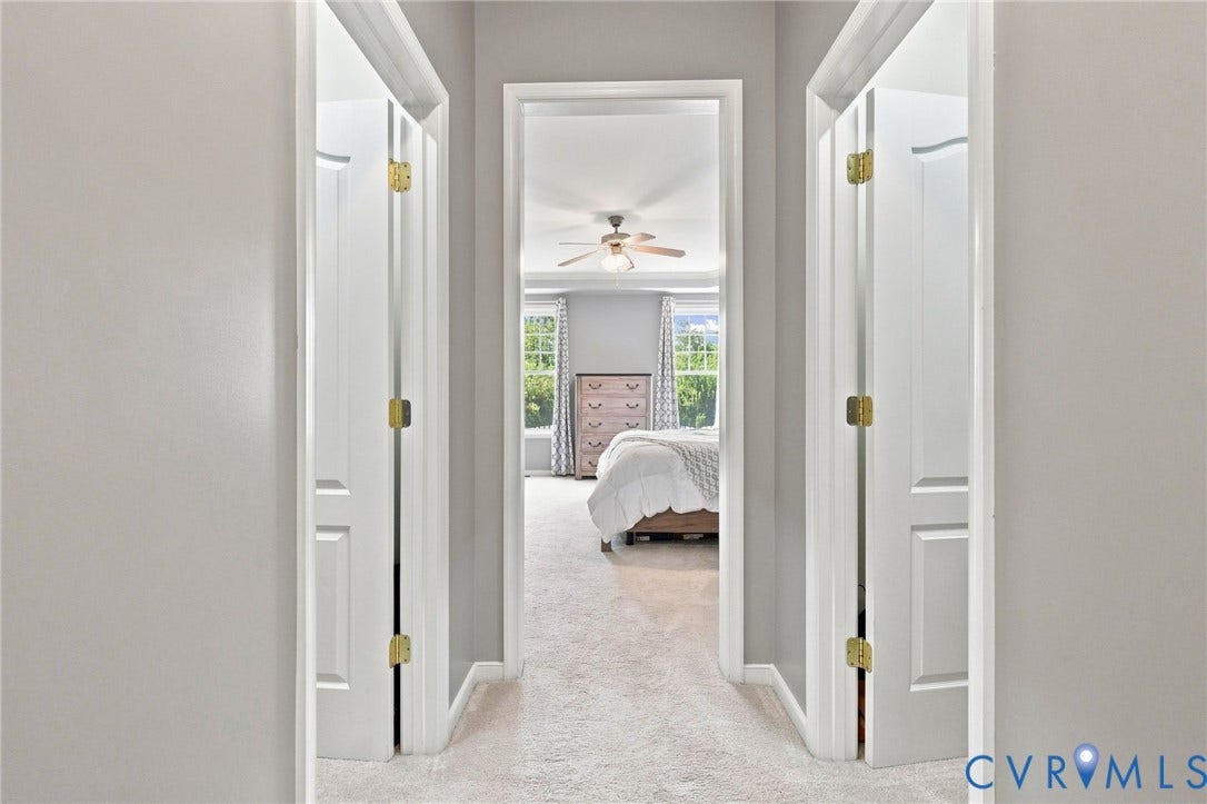 Hallway with light gray walls, white trim, and carpeted flooring