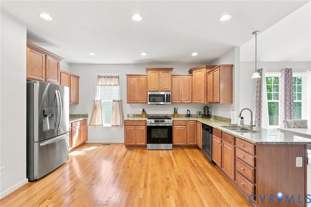 Kitchen featuring wood-finish flooring, stainless steel appliances, upper and lower wood cabinetry, recessed lighting, and a peninsula with a countertop