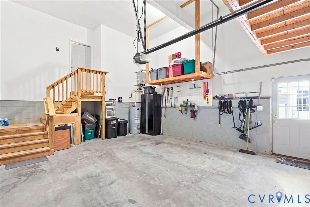 Concrete flooring, interior steps with wood railing, finished walls, overhead storage shelf, and a side entry door