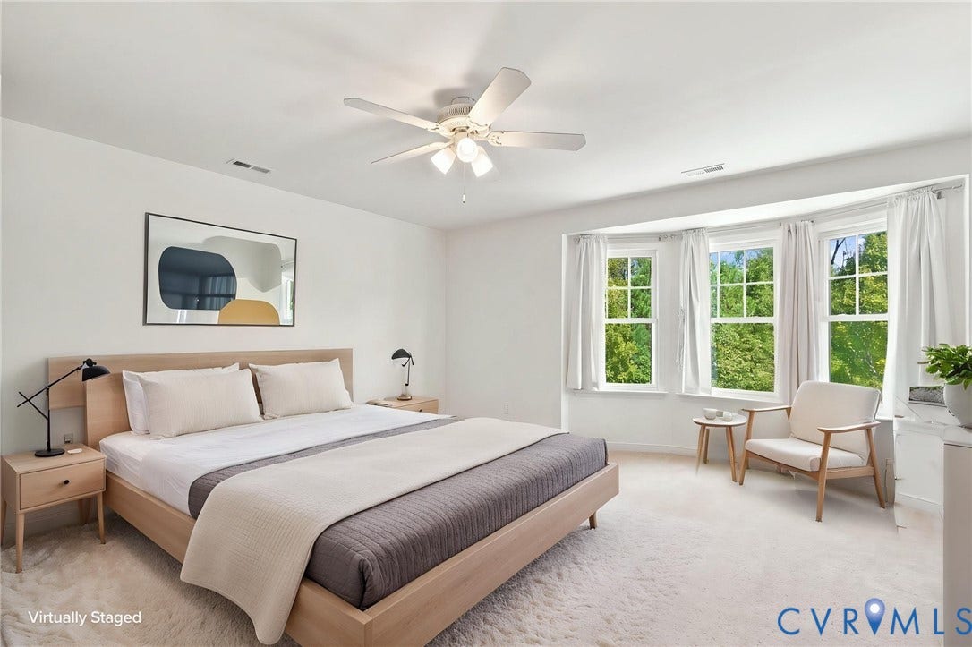Bay window with three paneled windows, ceiling fan with integrated lighting, and light-toned wall-to-wall carpeting
