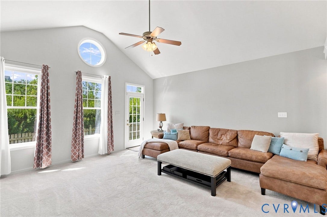 Vaulted ceiling featuring a ceiling fan, a circular architectural window, and multiple large windows