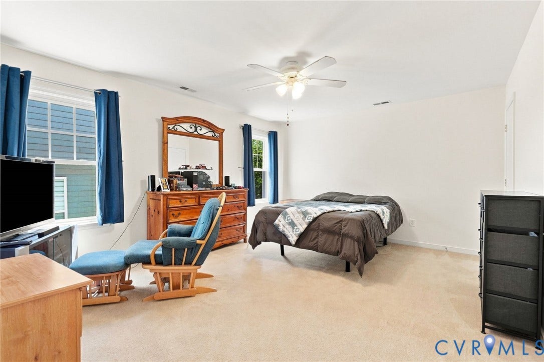 Expansive room with neutral carpeting and a ceiling fan