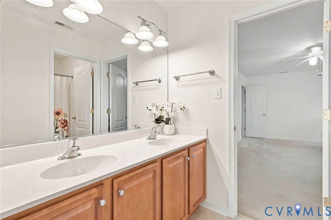Dual vanity with white countertop, chrome fixtures, and wood-finish cabinetry