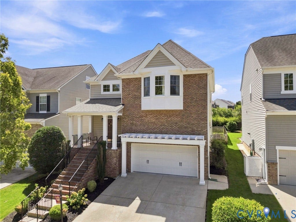Brick and siding exterior with a covered front porch, an attached two-car garage, and a concrete driveway