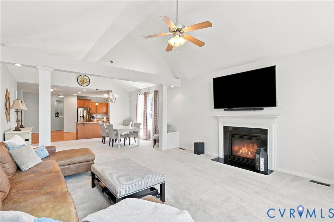 Vaulted ceiling with ceiling fan, built-in fireplace with mantle, and carpeted flooring