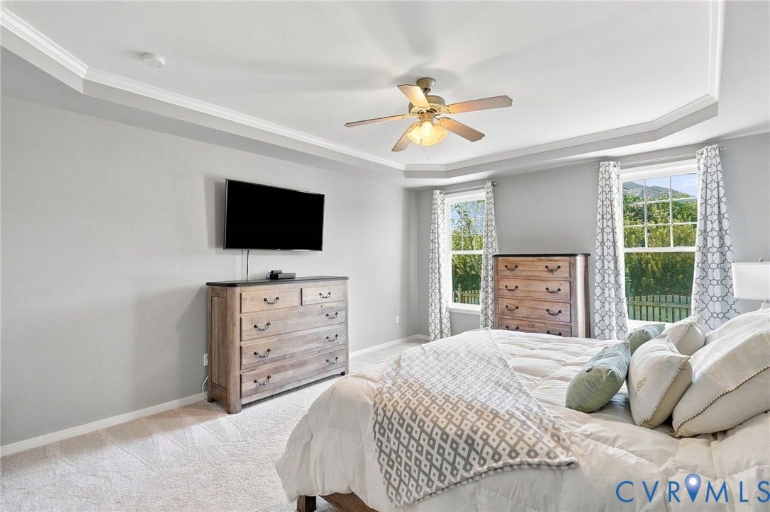 Tray ceiling with crown molding, ceiling fan, and light gray wall finishes