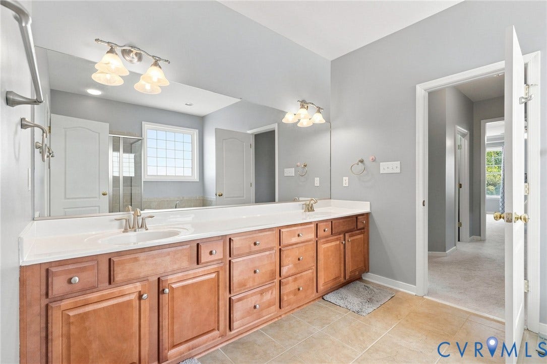 Dual vanity with wood-finish cabinetry, integrated sinks, and polished chrome fixtures