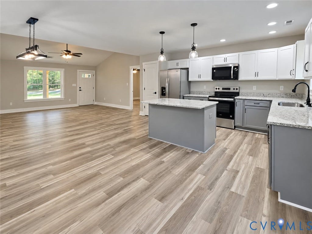 1010 Johnson Road, Mineral, VA 23117 Open-concept living space featuring wood-finish flooring, vaulted ceilings, and a kitchen with an island, stainless steel appliances, and granite countertops