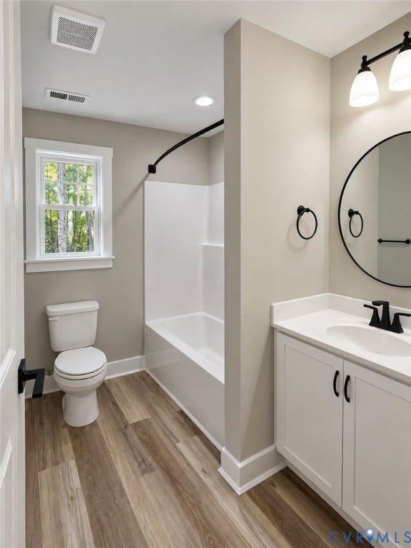 1010 Johnson Road, Mineral, VA 23117 Wood-finish flooring, white vanity with integrated sink, contemporary round mirror, bathtub with shower, and white trim window
