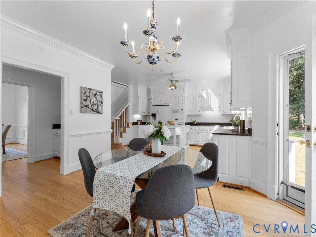 Open-concept living space featuring wood-finish flooring, white cabinetry, dark countertops, and a glass-paneled exterior door