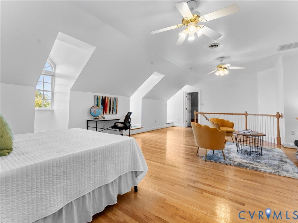 Expansive room featuring wood-finish flooring, multiple ceiling fans, and architectural dormer windows