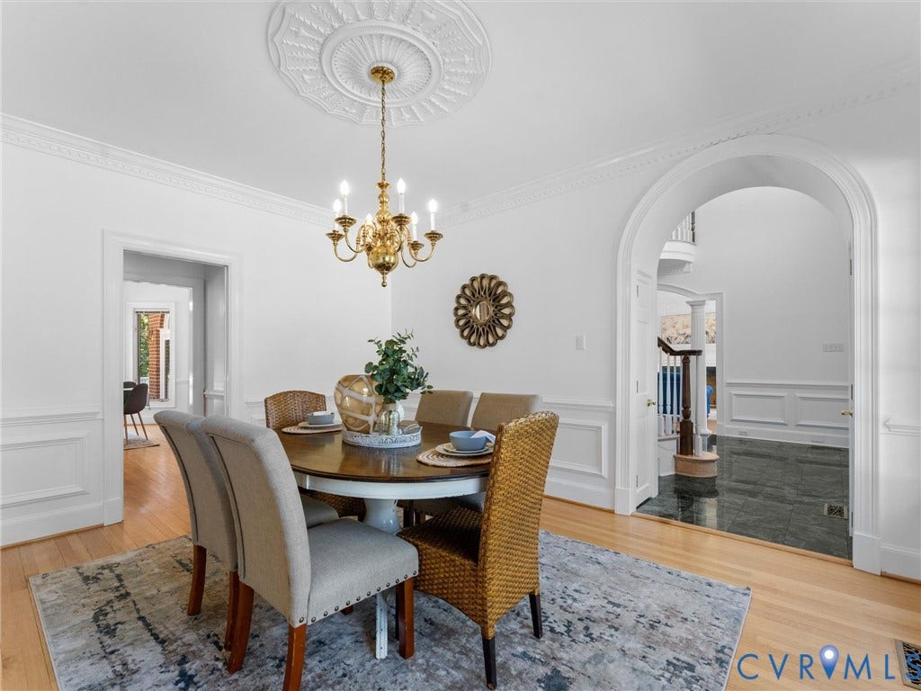 Hardwood flooring, decorative ceiling medallion, ornate chandelier, wainscoting, and arched doorway