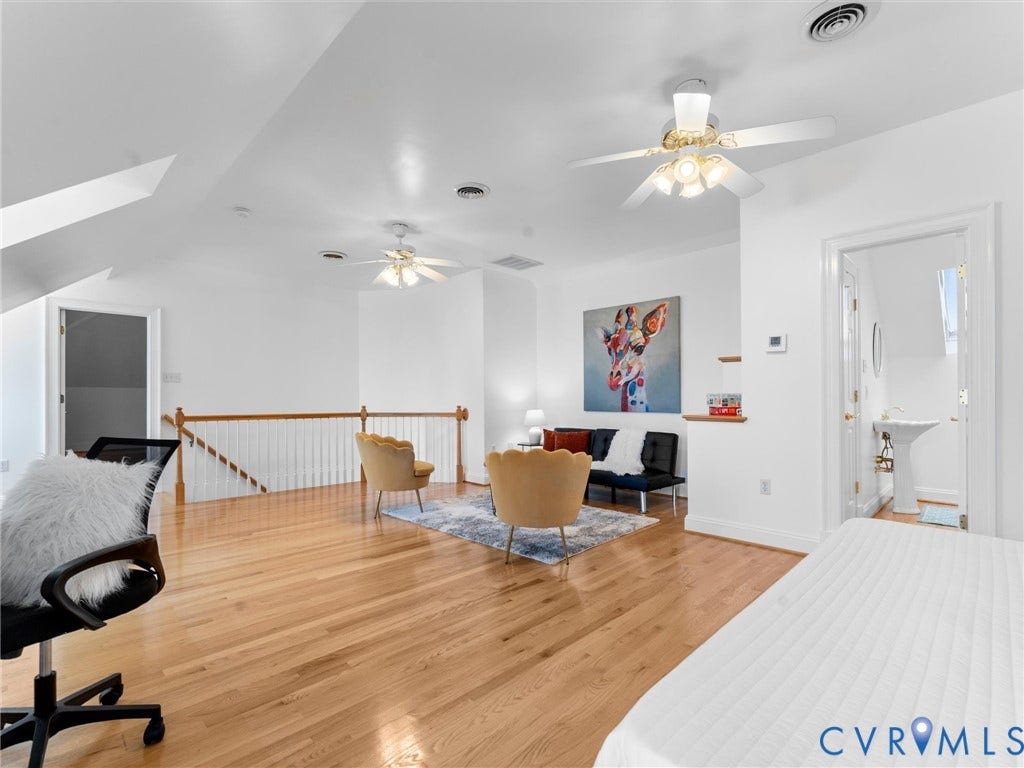 3rd floor, Hardwood flooring, white walls, angled ceilings, multiple ceiling fans, and a partial staircase with wood railing