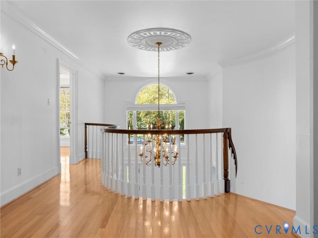 Hardwood flooring throughout, featuring a curved staircase with white balusters and a dark wood handrail
