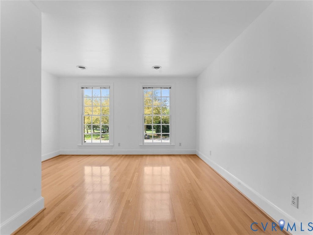Bright interior featuring two large windows, wood flooring, white walls, and recessed lighting