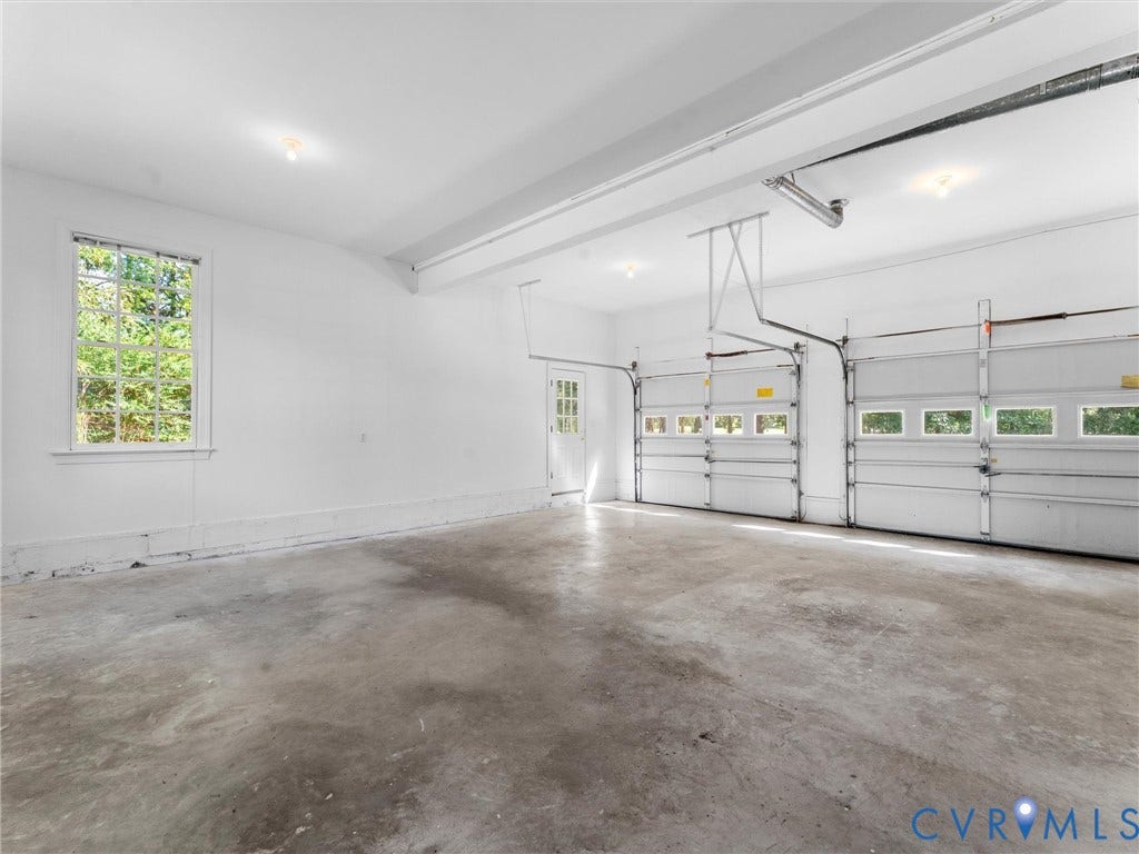 Two-car garage with concrete flooring, two overhead doors with window inserts, and an additional side entry door