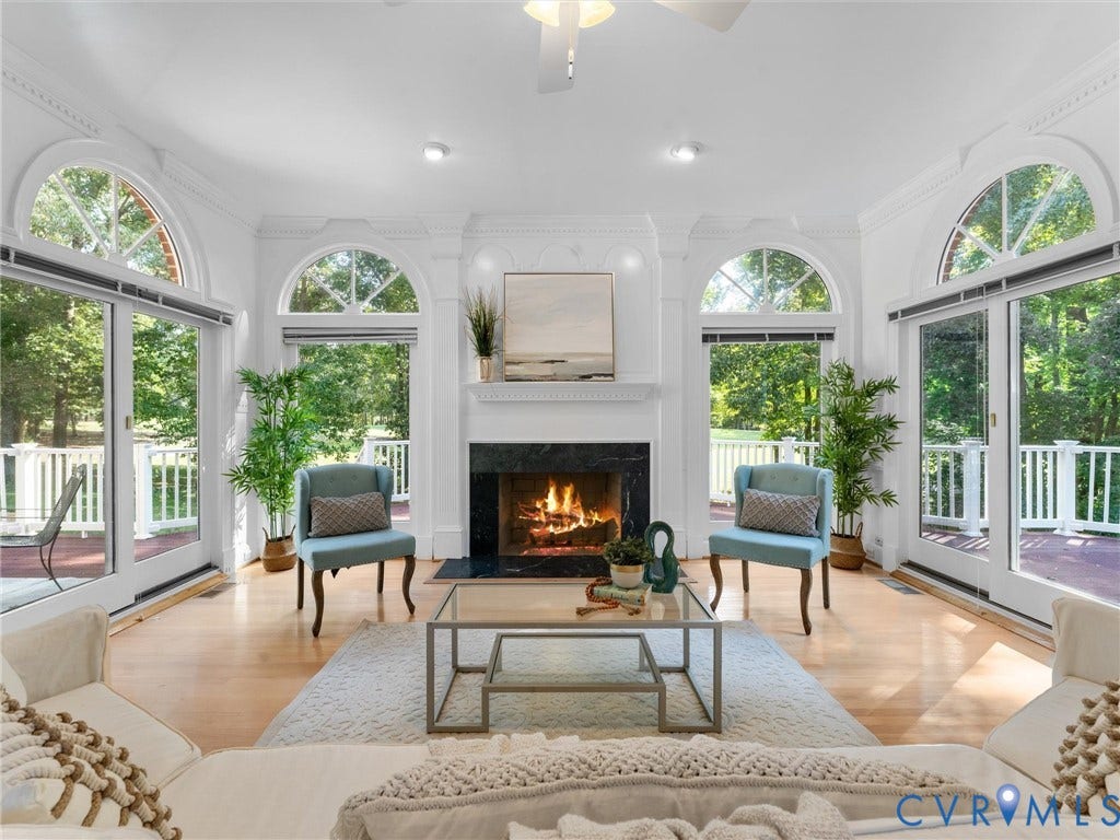 Hardwood flooring, fireplace with a dark stone surround, multiple arched windows, recessed lighting, and a ceiling fan