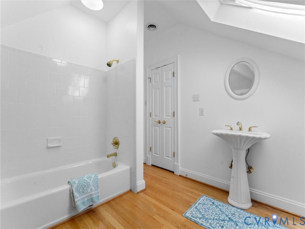 3rd floor, Pedestal sink with brass-finish faucet, white subway tile tub surround, and wood-finish flooring