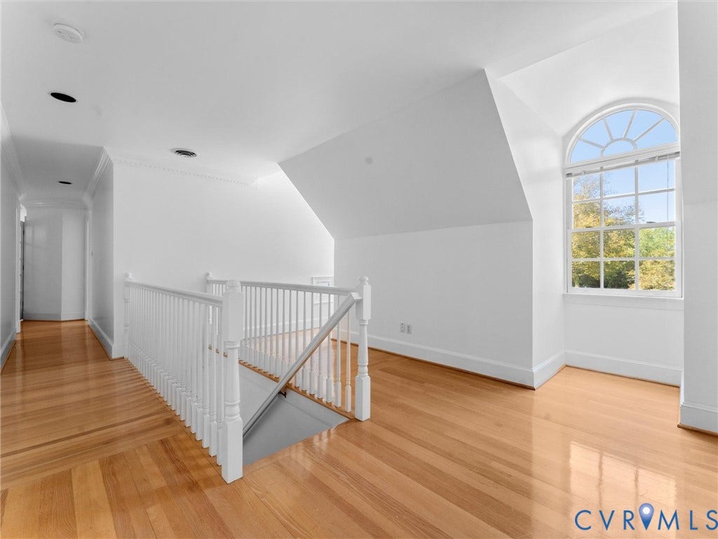 Hardwood flooring, white painted balustrade, arched window, recessed lighting, and crown molding