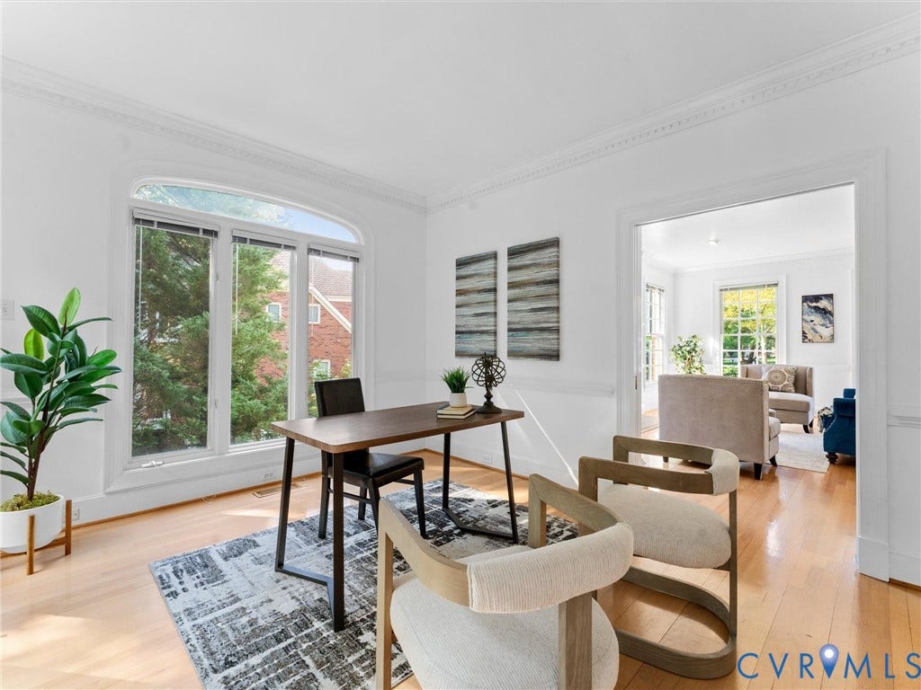 Hardwood flooring, arched window with multiple panes, crown molding, white painted walls, and a wide cased opening to living room w/ pocket doors