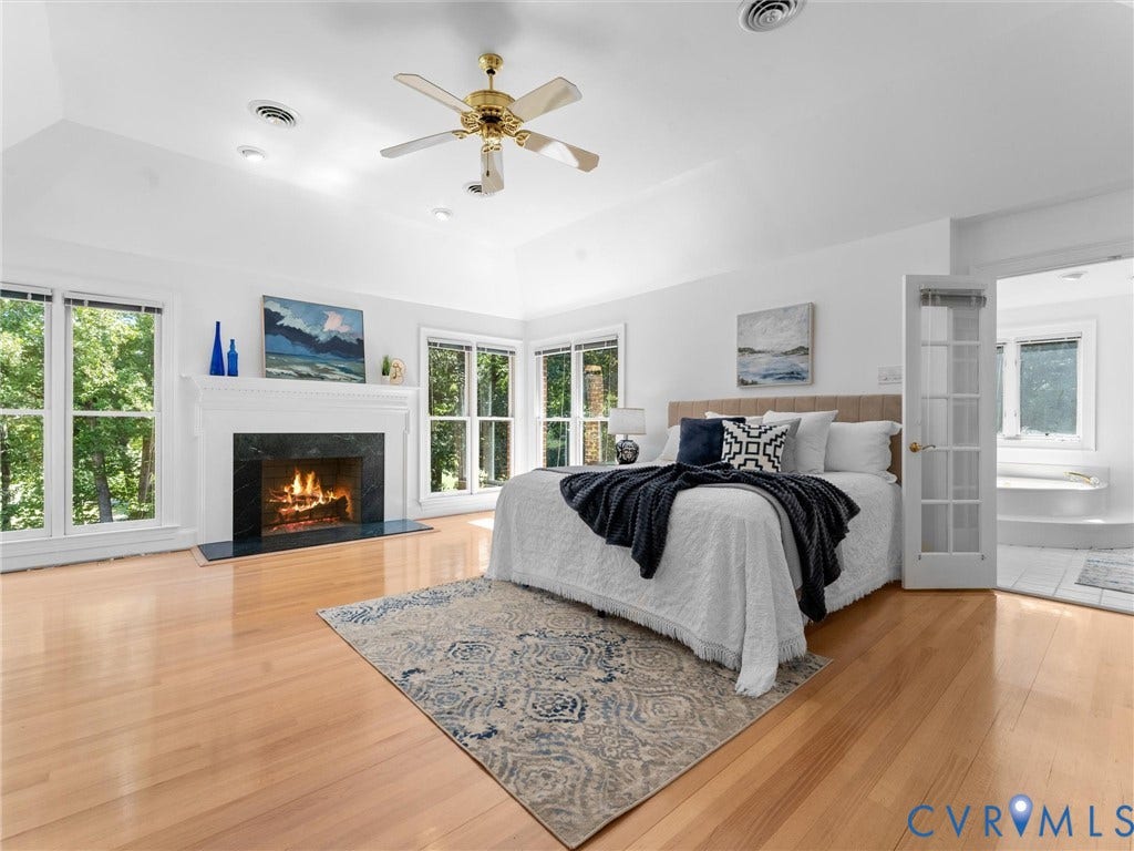 Cathedral ceiling with a ceiling fan, light wood-finish flooring, and multiple windows