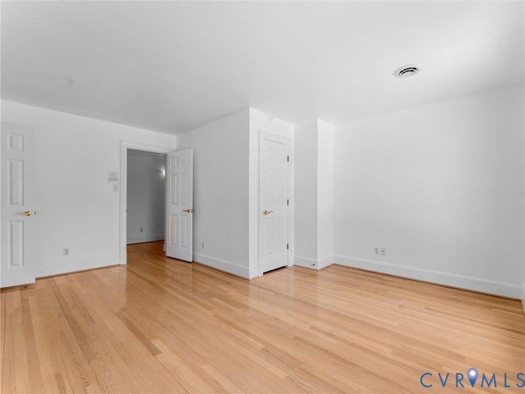Hardwood flooring with a natural finish, white walls, and white paneled doors
