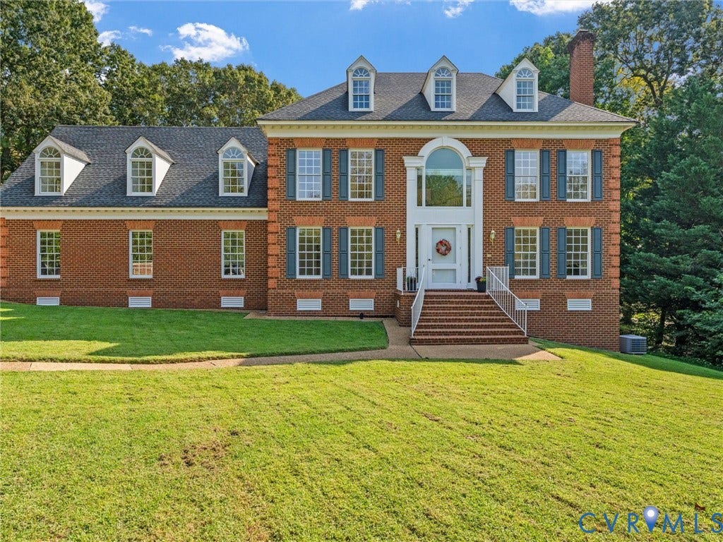 Red brick colonial-style residence with a prominent front entrance featuring an arched transom window