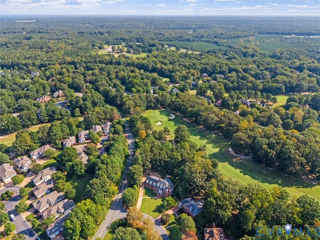Expansive green space and mature trees define the surrounding environment, with a golf course fairway prominent