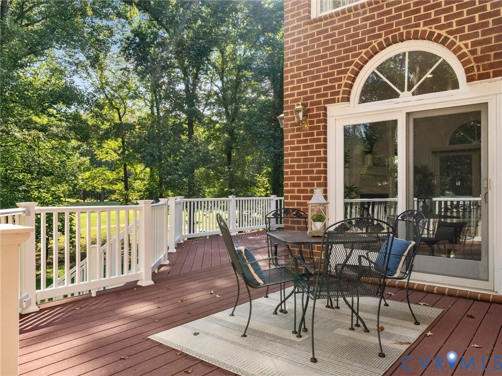 Spacious outdoor deck with composite decking, white railing, brick exterior, and arched transom window above sliding glass doors