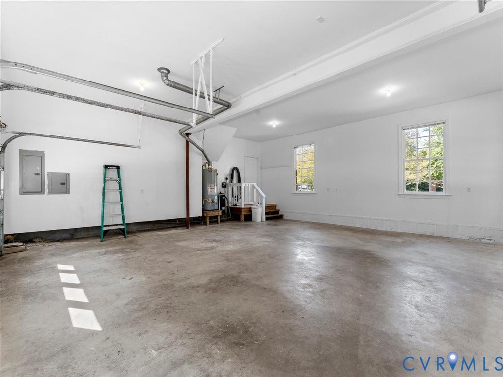Spacious garage with concrete flooring, two windows, recessed lighting, and internal staircase access