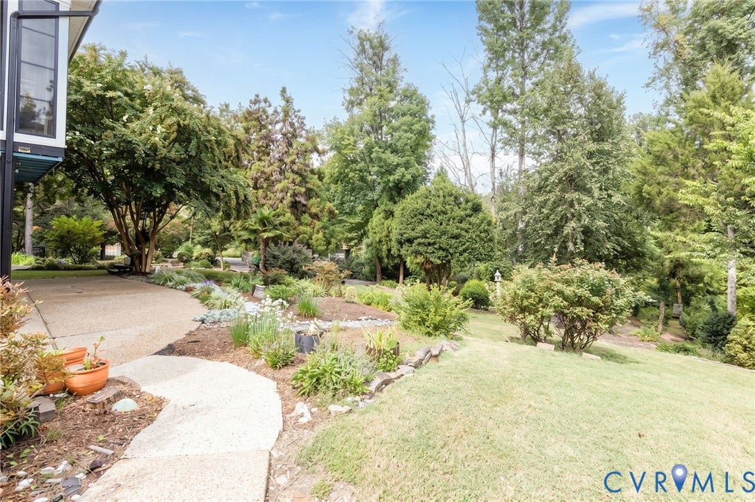 12669 Fawn Lane, Goochland, VA 23233 Mature landscaping featuring a variety of trees and shrubs, a curved concrete pathway, and a gravel surface