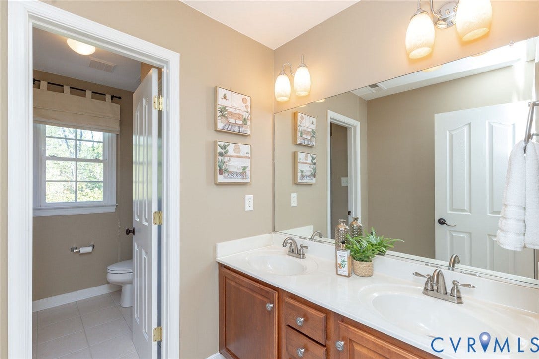 12669 Fawn Lane, Goochland, VA 23233 Double vanity with white countertops, wood-finish cabinetry, and polished chrome fixtures